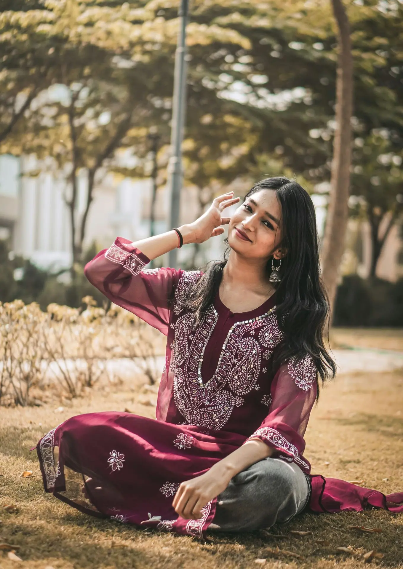 a woman sitting on the ground wearing a maroon dress